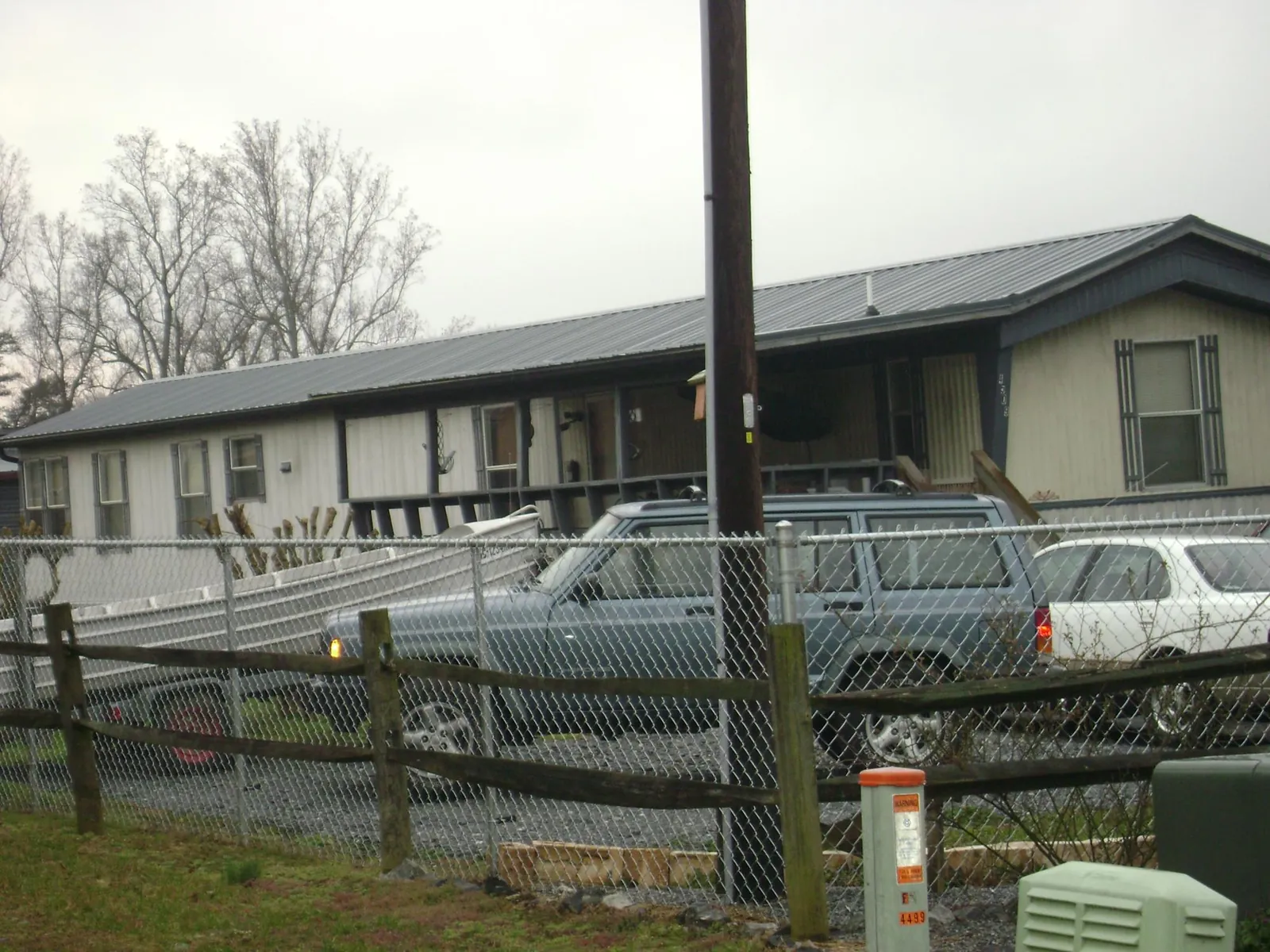 Dark metal roof on a long single story building behind a chain link fence in Immokalee