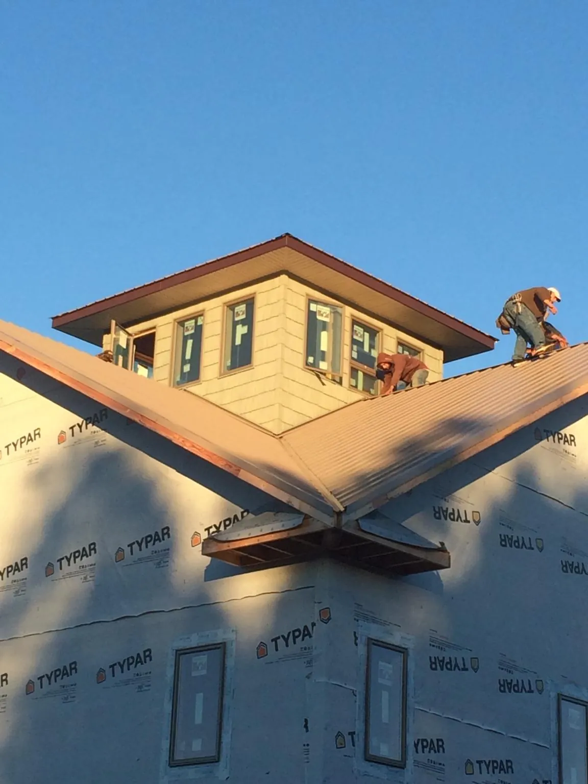 Roofers working around a rooftop cupola on a new metal roof at sunset — Roof Waterproofing in Immokalee by Roofing Brothers